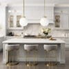 Interior of modern luxurious kitchen classic style. White cabinets with gilded handles, kitchen island with white marble countertop, built-in home appliances, vintage pendant lights. Home design